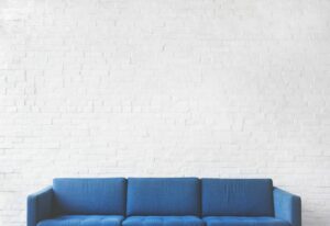 blue couch against a white brick wall